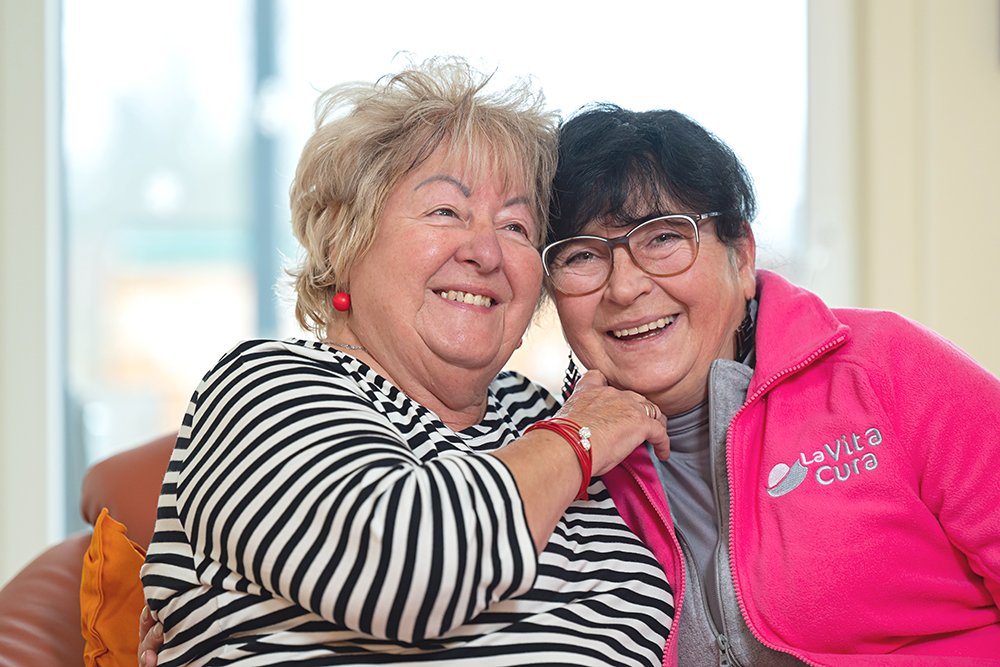 Mitarbeiterin der LaVitaCura Pflegedienst GmbH mit älterer Dame, beide lächeln in die Kamera ©LaVitaCura Pflegedienst GmbH
