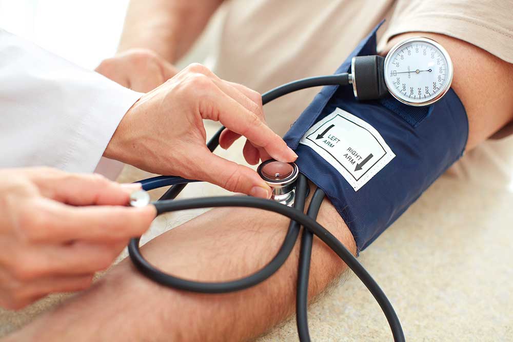 Blaue Blutdruckmanschette am Arm eines Patienten